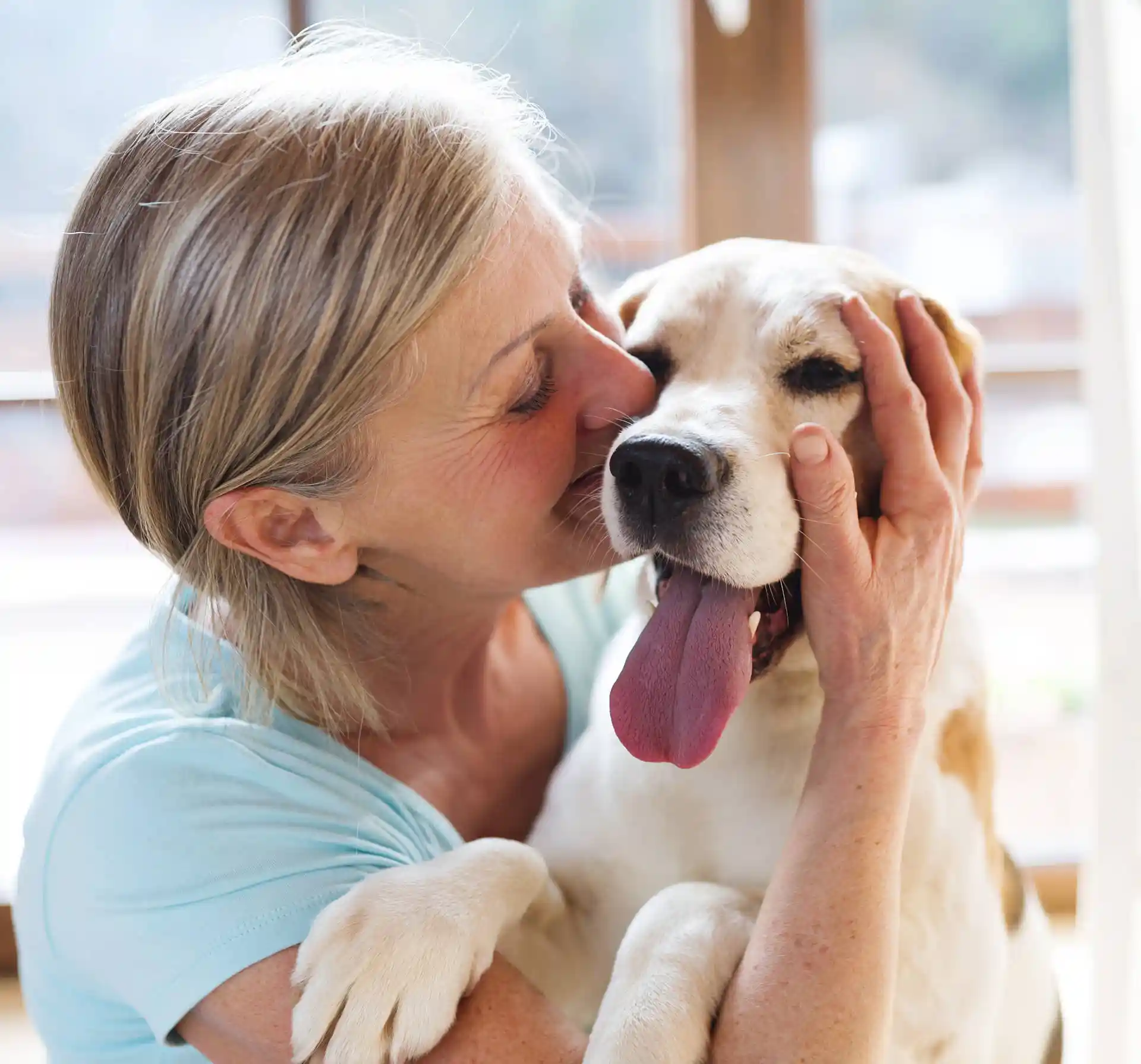 Woman holding a young dog against her face